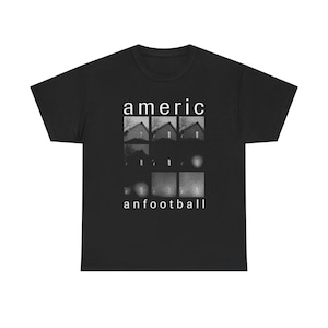 Op de afbeelding: Zwart T-shirt met een grafisch ontwerp. Het ontwerp toont het woord "americ" boven een reeks grijswaardenafbeeldingen van huizen en bollen, met het woord "anfootball" eronder. Het shirt is gemaakt van een zacht, comfortabel materiaal.