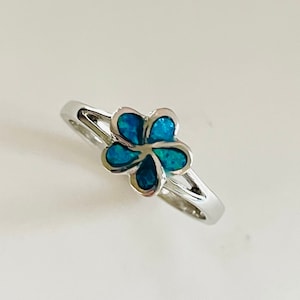 May include: A silver ring with a blue opal flower design.