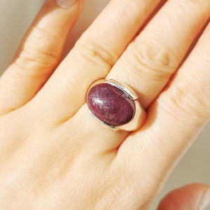 Peut inclure: Une bague en argent avec une grande pierre précieuse ovale de couleur violet foncé.