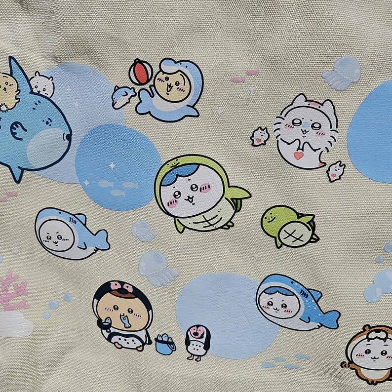 May include: A beige fabric featuring a repeating pattern of cartoon sea creatures, including sharks, dolphins, penguins, and turtles. The illustrations are in shades of blue, green, and white, with light blue circles and pink coral accents.