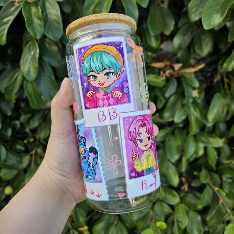 May include: A clear glass tumbler with a bamboo lid, decorated with cartoon images. The tumbler features illustrations of anime-style characters and the letters "BB" and "R". The design includes pink hearts and a blue cat illustration.