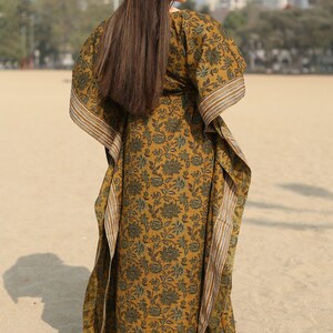 Puede incluir: Un vestido largo y fluido de kaft&aacute;n con estampado floral en tonos verdes y marrones. El vestido tiene un escote amplio y fluido y mangas largas. La tela es suave y c&oacute;moda, lo que lo hace perfecto para descansar o relajarse.