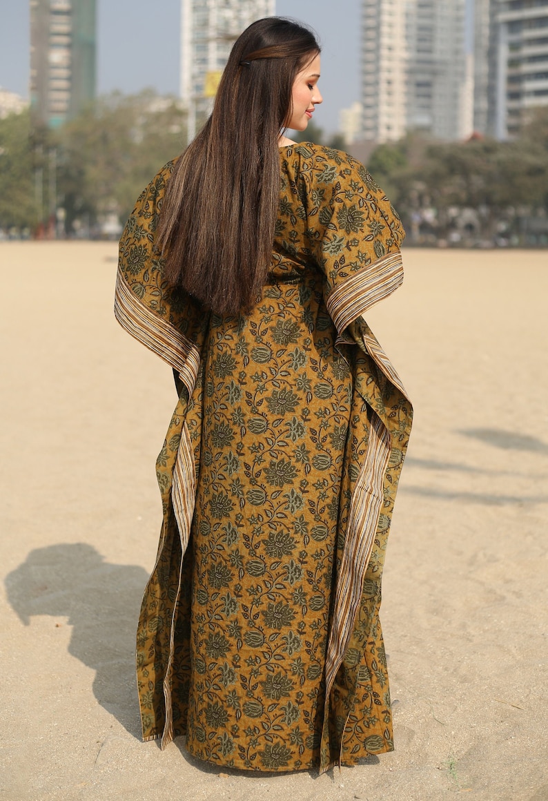 Puede incluir: Un vestido largo y fluido de kaft&aacute;n con estampado floral en tonos verdes y marrones. El vestido tiene un escote amplio y fluido y mangas largas. La tela es suave y c&oacute;moda, lo que lo hace perfecto para descansar o relajarse.
