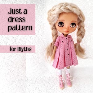 May include: A Blythe doll wearing a pink dress with black polka dots, white socks, and pink boots. The doll has blonde braided hair and brown eyes. Text on the left reads "Just a dress pattern for Blythe."