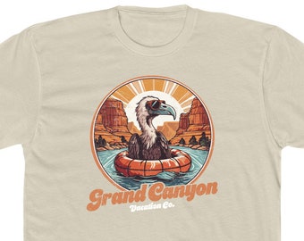 May include: A beige t-shirt with a vintage-style illustration of a cartoon vulture wearing sunglasses and floating on an orange inner tube in a river. The illustration is surrounded by a circle with the text "Grand Canyon Vacation Co."