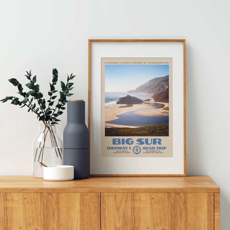 May include: A framed vertical wall art print featuring a scenic photograph of the Big Sur coastline in California. The print includes the text BIG SUR, HIGHWAY 1, ROAD TRIP, and geographical coordinates in a beige and blue color palette.