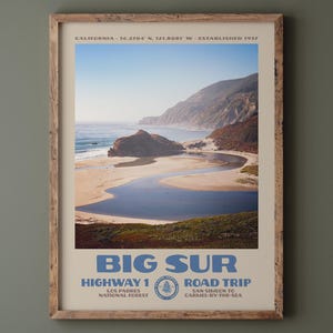 May include: A framed travel poster featuring a coastal landscape of Big Sur, California. The print displays a winding river meeting the ocean, cliffs, and text reading BIG SUR, HIGHWAY 1 ROAD TRIP, LOS PADRES NATIONAL FOREST, SAN SIMEON TO CARMEL-BY-THE-SEA.