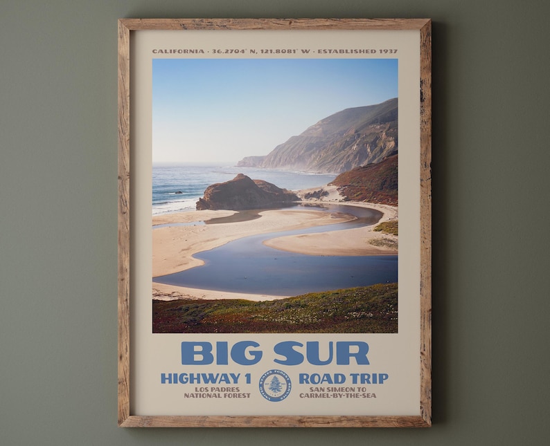 May include: A framed travel poster featuring a coastal landscape of Big Sur, California. The print displays a winding river meeting the ocean, cliffs, and text reading BIG SUR, HIGHWAY 1 ROAD TRIP, LOS PADRES NATIONAL FOREST, SAN SIMEON TO CARMEL-BY-THE-SEA.