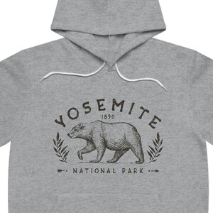 May include: Grey hooded sweatshirt with a black graphic print of a bear walking in front of a wreath with the text "Yosemite 1890 National Park".