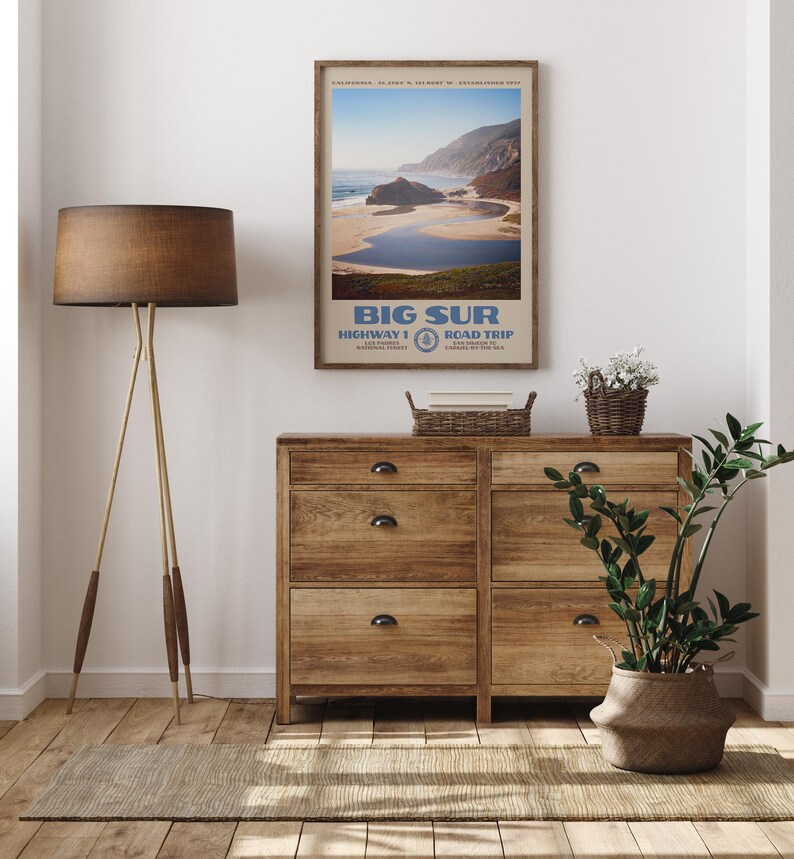 May include: A framed vertical wall art print featuring a scenic coastal landscape of Big Sur, California. The poster displays the text Big Sur, Highway 1, Road Trip, Los Padres National Forest, and California, with a blue ocean and sandy beach.