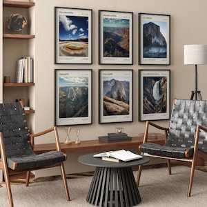 May include: Six framed landscape prints featuring national parks, including Yellowstone and Yosemite. The prints have black frames and are displayed on a beige wall above a wooden table and two black leather chairs. The room is decorated in a modern style.