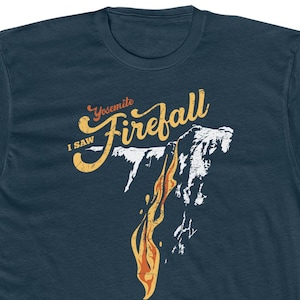 May include: A navy blue t-shirt with a vintage-style graphic of Yosemite Firefall. The graphic features the text "I SAW Yosemite Firefall" in a yellow and orange font.