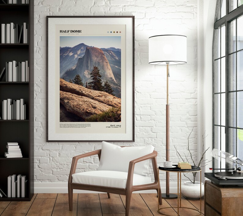 May include: Framed art print featuring a photograph of Half Dome in Yosemite National Park. The image shows the mountain with a clear sky, trees, and rocky foreground. The print has a white border and is in a dark brown frame. Text at the top reads "HALF DOME".