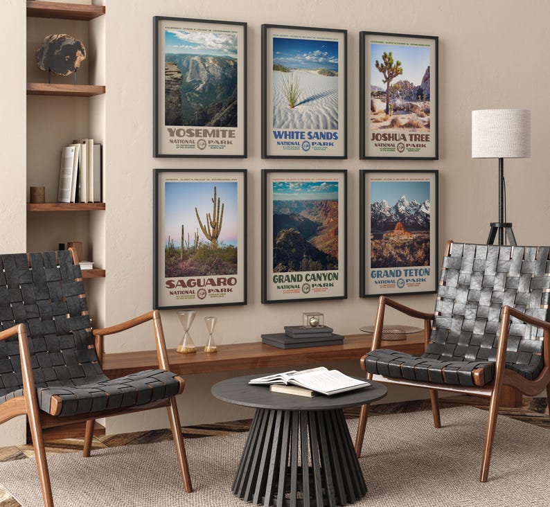 May include: A collection of framed National Park posters, including Yosemite, White Sands, Joshua Tree, Saguaro, Grand Canyon, and Grand Teton. The posters are displayed on a beige wall above a wooden console. Two black leather chairs and a round black table are in the foreground.