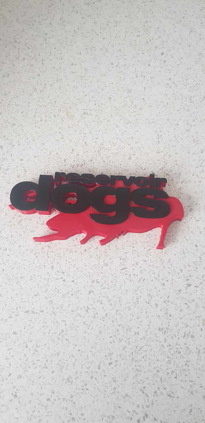 Op de afbeelding: Een 3D-geprint logo voor Reservoir Dogs, een populaire film, in rood en zwart.