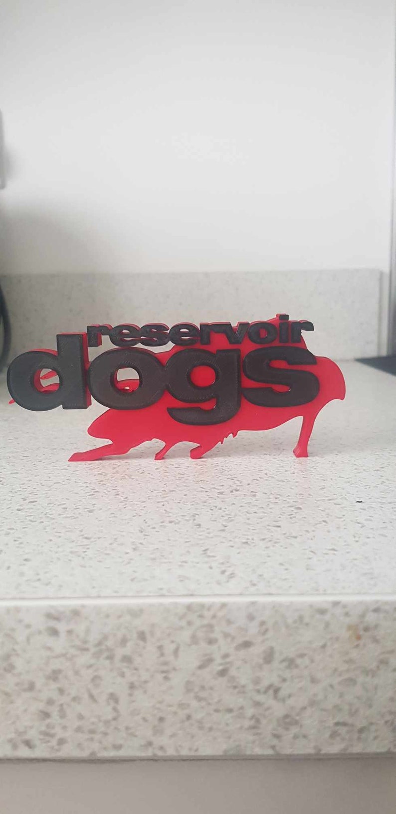 Op de afbeelding: Een rood en zwart 3D-geprint bord met de tekst "Reservoir Dogs".