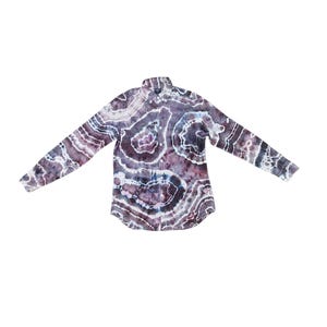 May include: A long-sleeve button-down shirt featuring a dark purple, black, and white tie-dye pattern that resembles concentric agate stone rings. The shirt has a standard collar, a front button placket, and a single chest pocket on the left side.