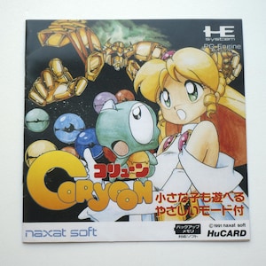 May include: A square video game manual for Coryoon on the PC Engine, featuring a blonde character and a green creature on the cover. The title Coryoon is printed in large yellow letters, with Japanese text, the Naxat Soft logo, and HuCARD branding.