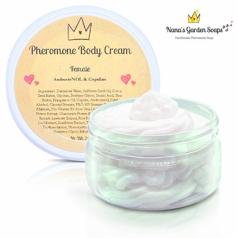 May include: A white jar with a cream-colored lid containing a white cream. The jar has a label that reads "Pheromone Body Cream Female AndrosteNOL & Copulins". The label also includes a crown and hearts. The jar is sitting on a white surface.