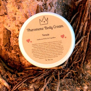 May include: A brown jar with a white lid and a label that reads "Pheromone Body Cream Female AndrosteNOL & Copulins". The jar is sitting on a tree trunk.