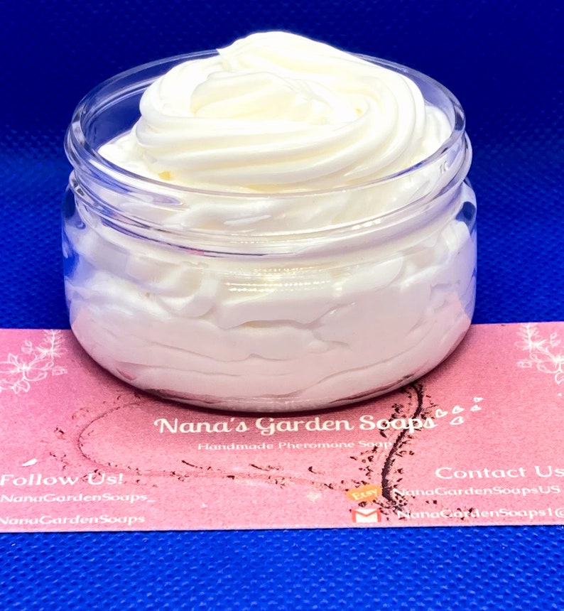 May include: A white, whipped body butter in a clear glass jar with a pink and white label that reads "Nana's Garden Soaps Handmade Pheromone Soaps". The label also includes the text "Follow Us! NanaGardenSoaps NanaGardenSoaps" and "Contact Us NanaGardenSoapsUS NanaGardenSoaps!"
