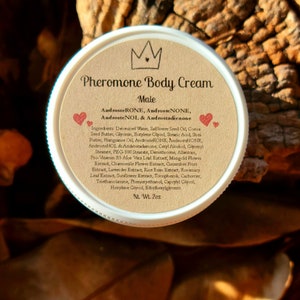 May include: A brown jar with a white lid labeled "Pheromone Body Cream Male" with a crown icon and two red hearts. The label lists ingredients including AndrosteRONE, AndrosteNONE, AndrosteNOL & Androstadienone. The jar is 2 oz.