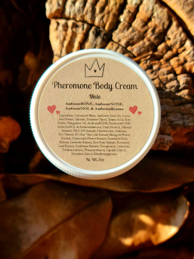 May include: A brown jar with a white lid labeled "Pheromone Body Cream Male" with a crown icon and two red hearts. The label lists ingredients including AndrosteRONE, AndrosteNONE, AndrosteNOL & Androstadienone. The jar is 2 oz.