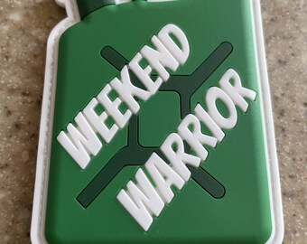 May include: Green and white patch with a white outline. The patch is shaped like a gas can and has a white cross with the words "Weekend Warrior" written diagonally across it.