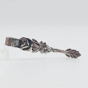 Peut inclure: Pince à sucre en argent avec un motif de rose et de feuilles.