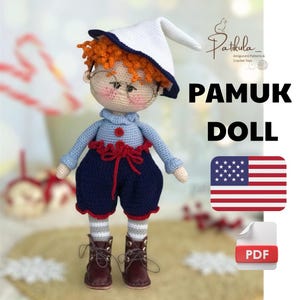 May include: Crochet doll pattern for a cute boy doll wearing a blue and red outfit, a white hat, and glasses. The pattern is available as a PDF download. The image also includes the text "Pamuk Doll" and a US flag.