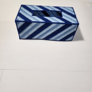 May include: Blue and white striped tissue box cover. The cover is made of plastic canvas and has a diagonal stripe pattern.