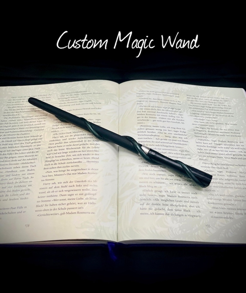 Pode incluir: Uma varinha m&aacute;gica preta e verde com um design retorcido em forma de videira. A varinha est&aacute; apoiada em um livro aberto com texto em alem&atilde;o. O t&iacute;tulo do livro &eacute; "Custom Magic Wand".