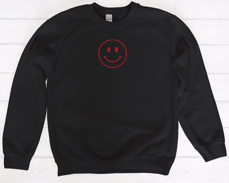 May include: Black sweatshirt with a red smiley face graphic.