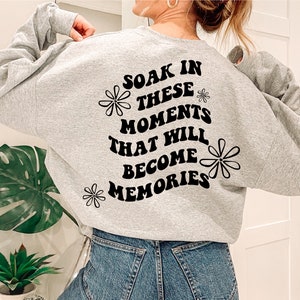 May include: Gray sweatshirt with black text that reads "Soak in these moments that will become memories" with a daisy graphic on the back.