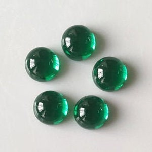 May include: Six round, green glass cabochons. The cabochons are smooth and shiny.