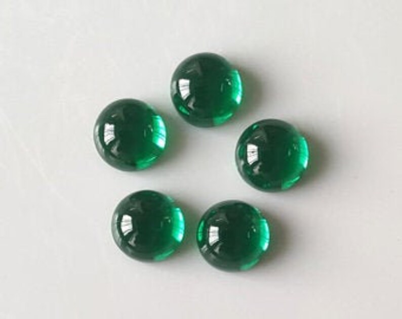 May include: Six round, green glass cabochons. The cabochons are smooth and shiny.