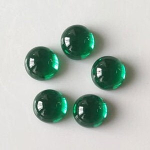 May include: Six round, green glass cabochons. The cabochons are smooth and shiny.