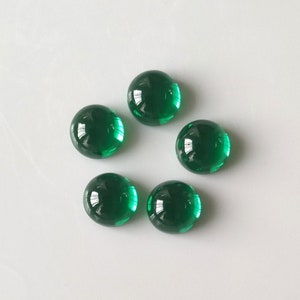 Pode incluir: Seis cabochões redondos de vidro verde. Os cabochões são lisos e brilhantes.