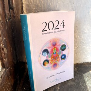 Puede incluir: Una agenda rosa y blanca 2024 con el texto "Diario Anual del Oraculo" e "Isis Medialdea Llaarden" en la portada. La portada presenta una ilustración colorida de una persona sentada en posición de loto con cinco círculos a su alrededor.