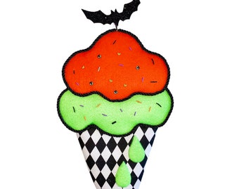 May include: A Halloween-themed decorative ice cream cone. The top layer is orange, the middle layer is green, and the cone is black and white checkered. A black bat tops the ice cream.