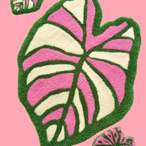 Puede incluir: Tres alfombras en forma de hoja de color rosa y verde con un centro blanco. Las alfombras están hechas de un material esponjoso y tienen una superficie texturizada.