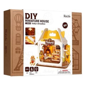 May include: A Rolife DIY Miniature House kit titled Teddy's Breadbox, featuring a brown cardboard box with white panels. The box displays a small bakery model with a yellow roof, a yellow door, and interior details like bread and a bear figure.