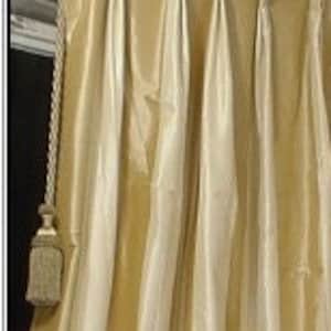 May include: Gold and ivory striped curtains with pleats hanging in a window. The curtains are made of a silky fabric.