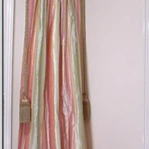 May include: A pair of pink and green striped curtains with a floral pillow in front of a white door.