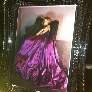 Puede incluir: Fotograf&iacute;a enmarcada de una mujer con un vestido morado vibrante. El vestido tiene una falda voluminosa. El marco es transparente con un dise&ntilde;o facetado, agregando elegancia al retrato.