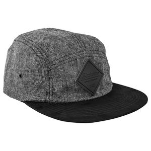 May include: A five-panel cap featuring a grey tweed crown and a black suede brim. A black diamond-shaped patch with the brand name is centered on the front. The cap has a structured design and a flat brim.