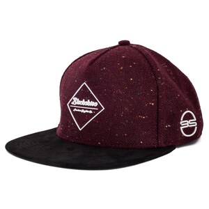 Può includere: Cappellino da baseball bordeaux e nero con visiera piatta. Il cappellino presenta un logo bianco a forma di diamante con la scritta "Blackskies" e un logo "BS" sul lato. Il cappellino ha una trama maculata.