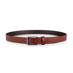 May include: A brown leather belt with a dark metal buckle. The belt is a medium brown color with a darker brown interior. The buckle is rectangular and has a matte finish. The belt is designed for use with pants.