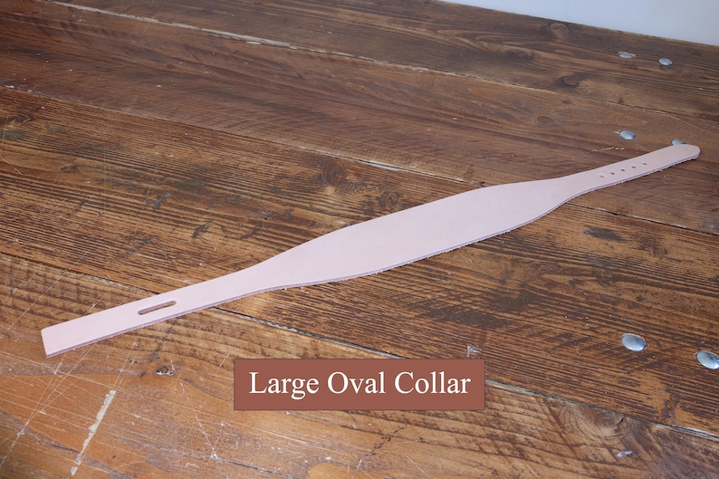 Peut inclure: Un collier en cuir rose clair avec une partie centrale large et ovale qui se r&eacute;tr&eacute;cit vers les extr&eacute;mit&eacute;s. Une extr&eacute;mit&eacute; pr&eacute;sente une fente rectangulaire, tandis que l'autre poss&egrave;de une s&eacute;rie de petits trous circulaires. Le texte Large Oval Collar est visible.