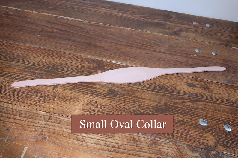 Peut inclure: Une pi&egrave;ce de cuir lisse, allong&eacute;e et de couleur beige clair, dot&eacute;e d'une section centrale ovale plus large et d'extr&eacute;mit&eacute;s effil&eacute;es, avec le texte "Small Oval Collar" imprim&eacute; en blanc sur un fond rectangulaire marron sous l'objet.